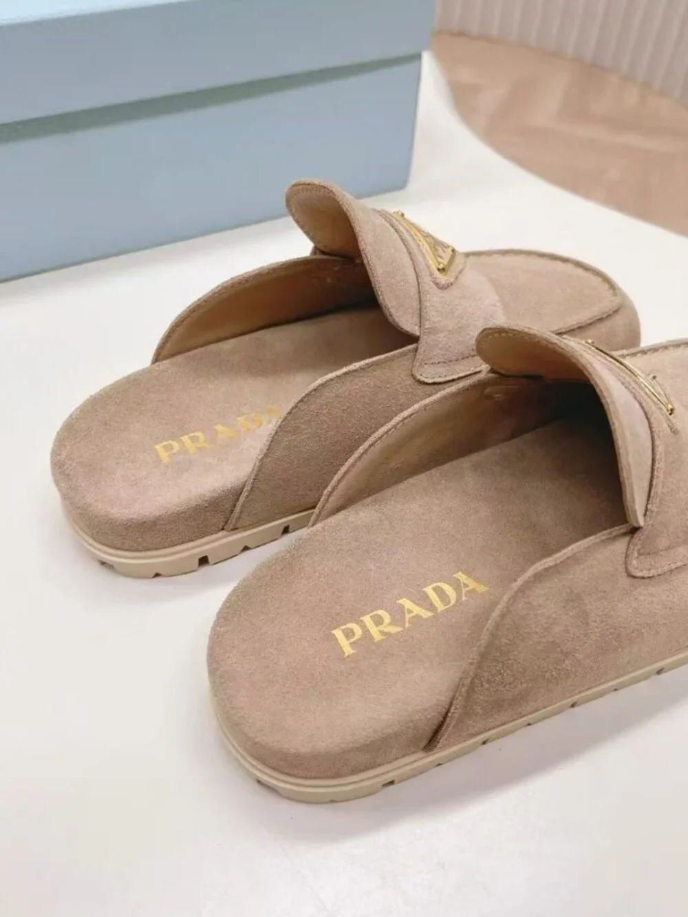 Prada beige slip‑on mules with triangular logo badge